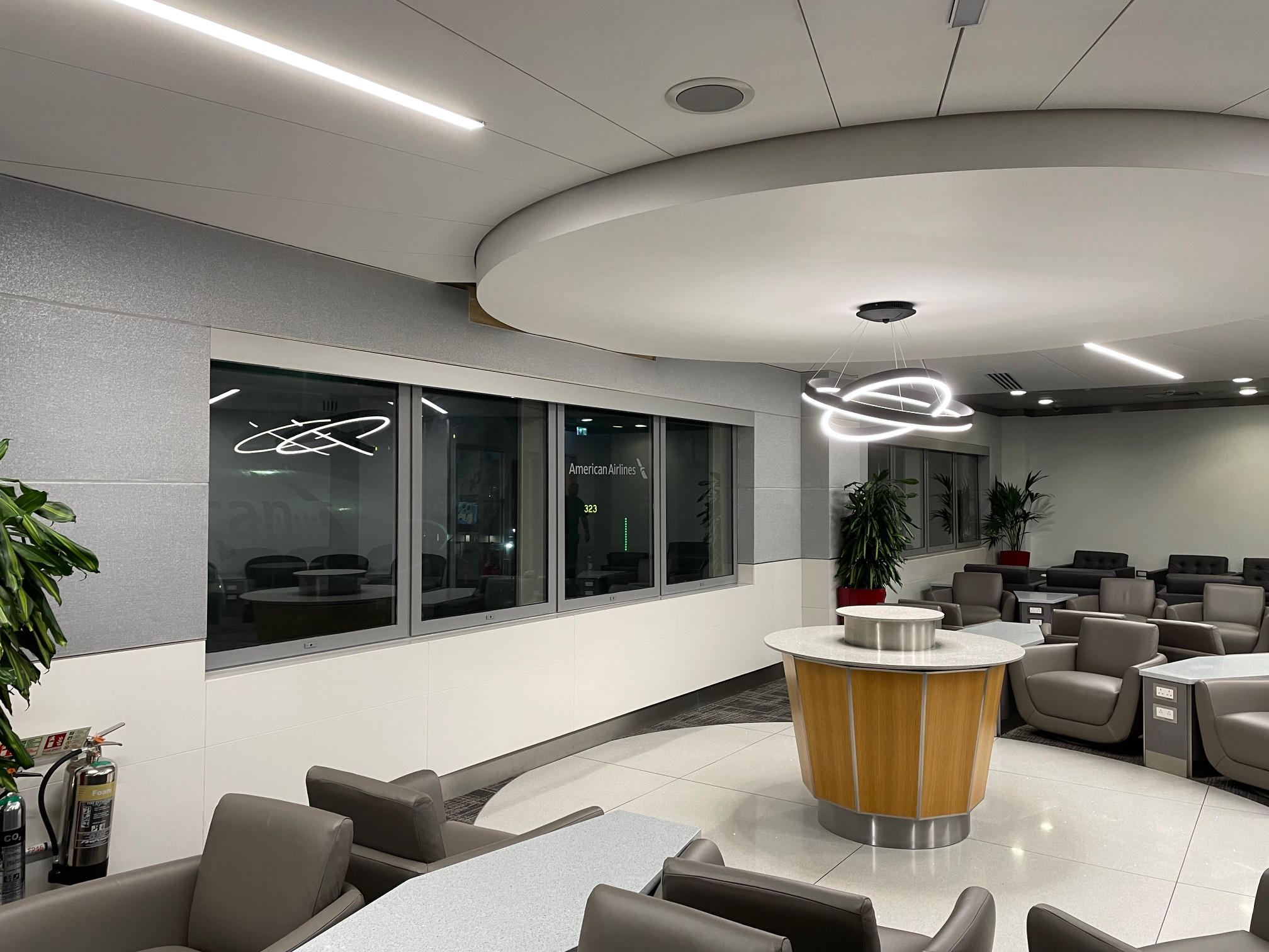 Modern airport lounge with a round table, windows, and a view of planes